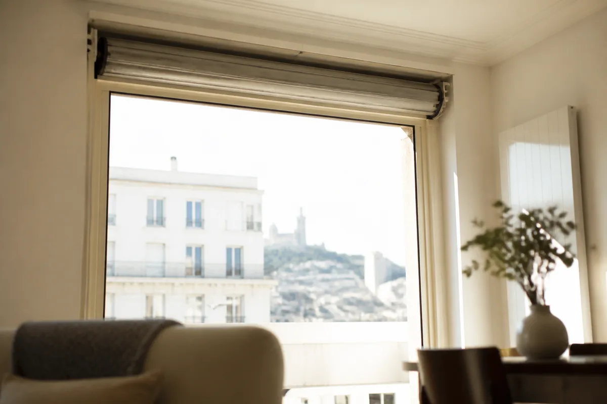 Volet roulant aluminium bloqué en haut sur une fenêtre d&rsquo;appartement marseillais, tablier entièrement enroulé