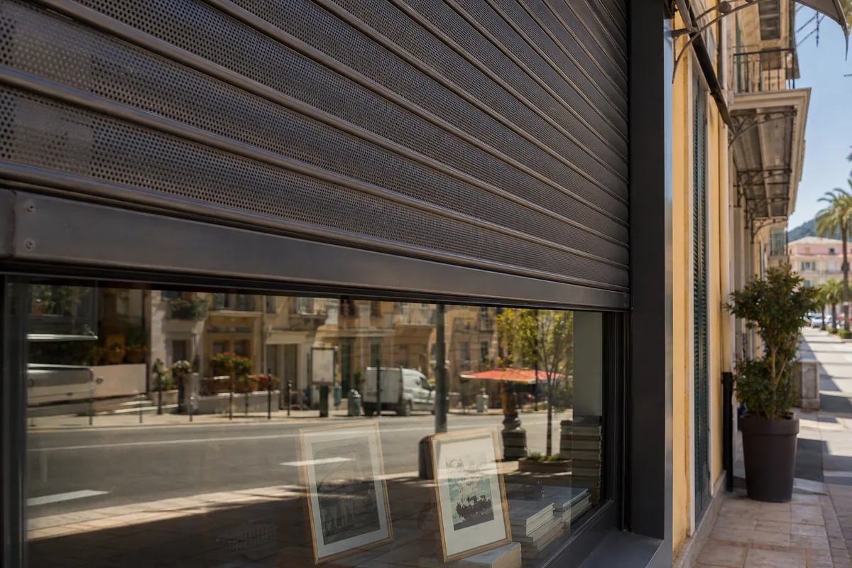 Rideau métallique de commerce à demi baissé sur une rue commerçante du sud